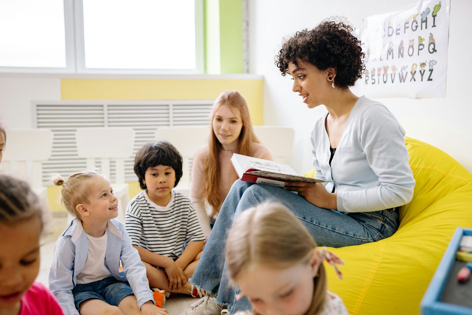 Teacher reading to children in classroom circle; nurturing education setting.