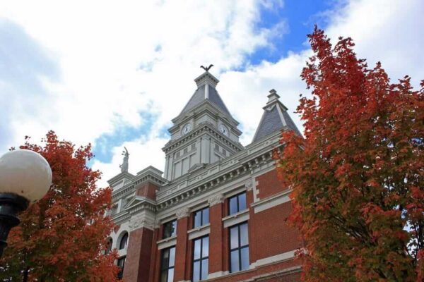 Historic courthouse with red brick facade and autumn trees, showcasing architectural heritage.