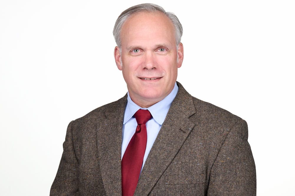 Professional headshot of man on white background.