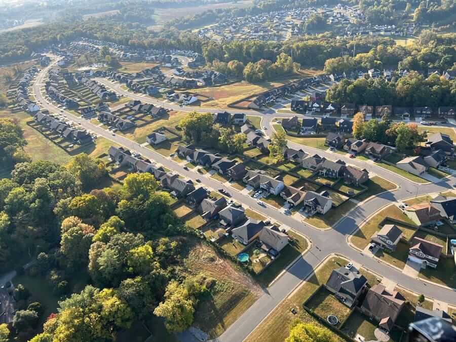 Aerial view of a suburban neighborhood with tree-lined streets and residential homes.